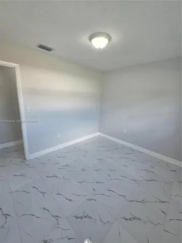 a kitchen with granite countertop a coffee maker a sink and white cabinets