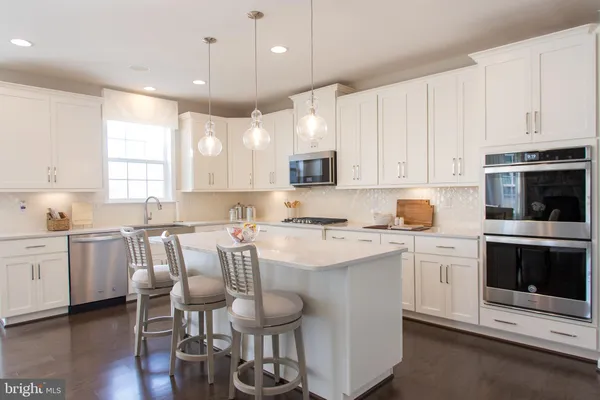 a kitchen with a dining table chairs sink and white cabinets