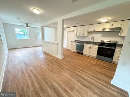a large kitchen with stainless steel appliances granite countertop a lot of cabinets and wooden floor