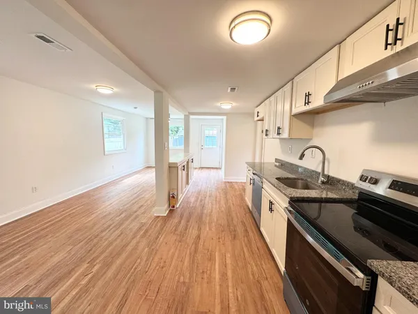 a kitchen with stainless steel appliances granite countertop a sink a stove and wooden floor