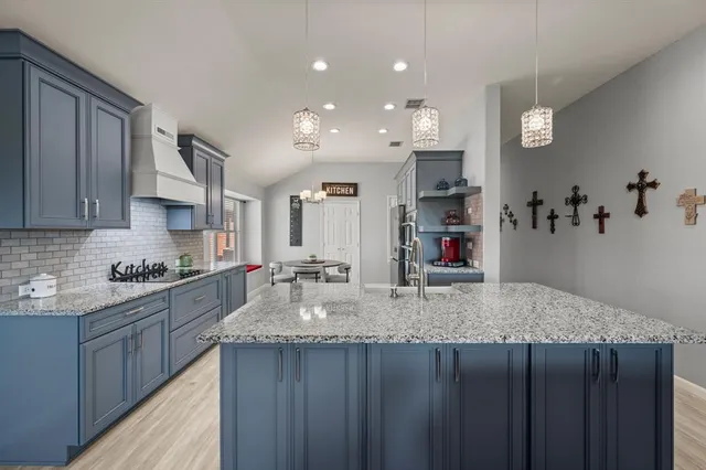 a kitchen with kitchen island granite countertop wooden cabinets and a refrigerator