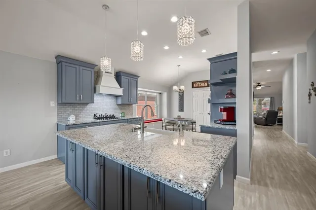 a kitchen with kitchen island a counter top space a sink cabinets and stainless steel appliances