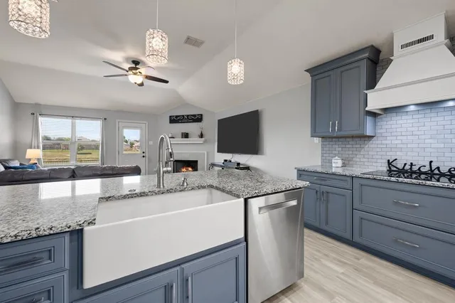 a kitchen with granite countertop a sink stainless steel appliances and cabinets