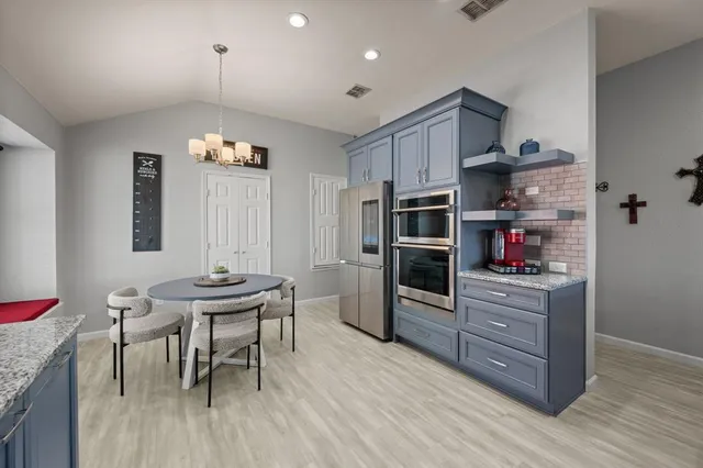 a kitchen with stainless steel appliances kitchen island granite countertop a table and chairs in it