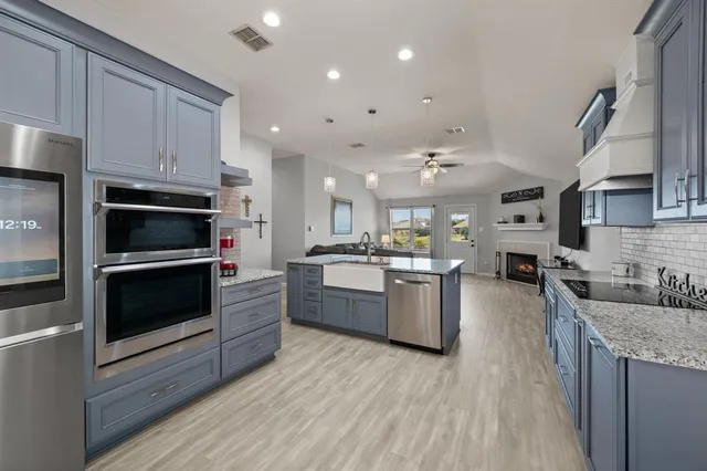 a kitchen with stainless steel appliances kitchen island granite countertop a stove a sink and a refrigerator