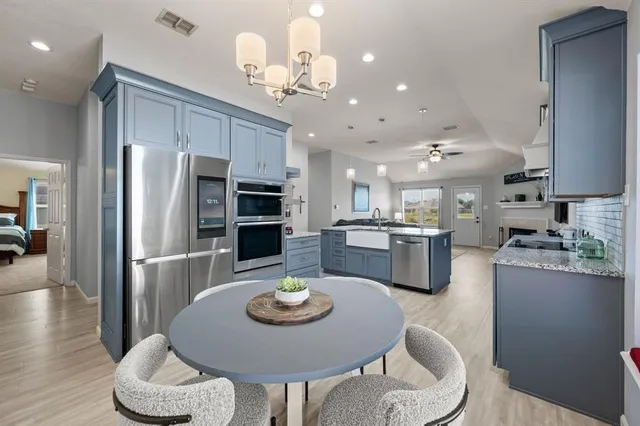 a kitchen with stainless steel appliances granite countertop a dining table and chairs