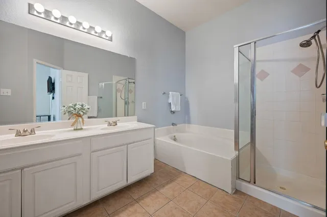 a spacious bathroom with a tub a sink shower and mirror