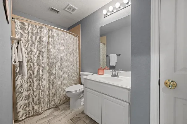 a bathroom with a sink a toilet and shower curtain