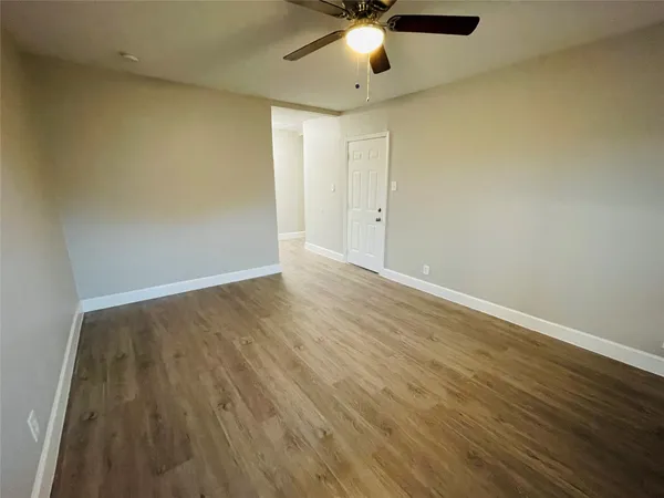 an empty room with wooden floor chandelier fan and windows