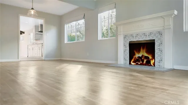 an empty room with wooden floor fireplace and windows