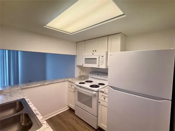 a kitchen with granite countertop a white cabinets and white appliances