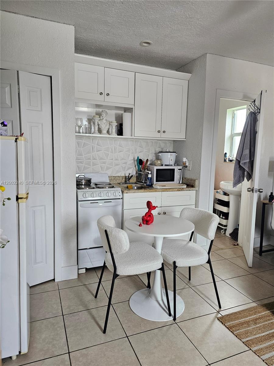 a kitchen with stainless steel appliances kitchen island granite countertop a table chairs refrigerator and sink