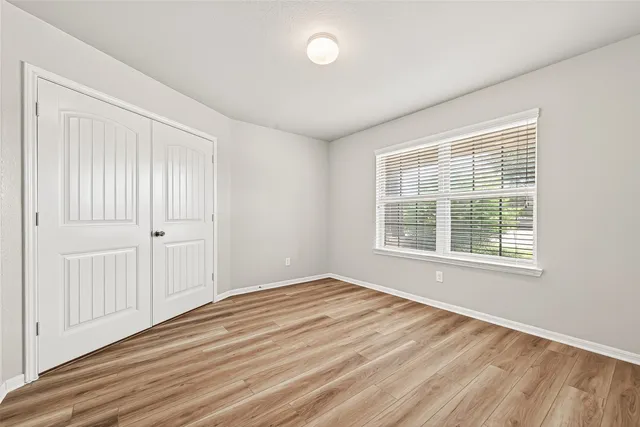 a view of an empty room with wooden floor and a window