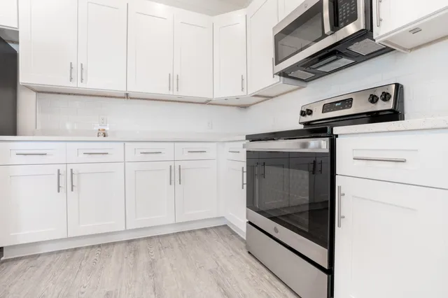 a kitchen with white cabinets and stainless steel appliances