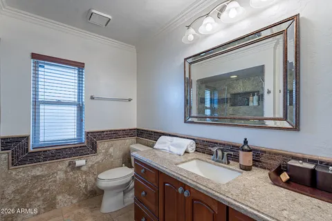 a bathroom with a granite countertop sink a toilet and mirror