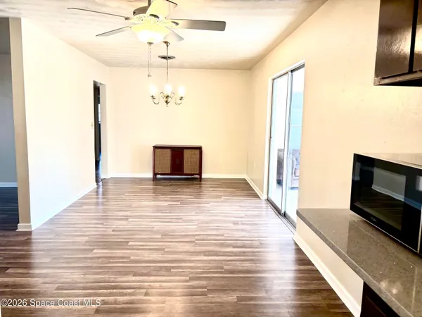a view of a livingroom with a fireplace a ceiling fan and wooden floor