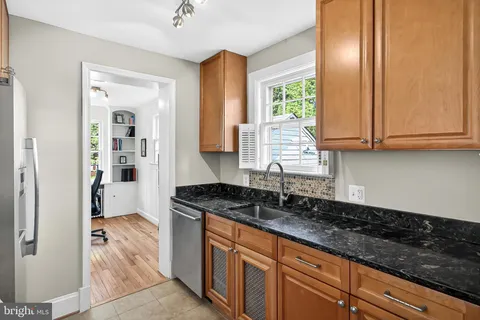 a kitchen with granite countertop stainless steel appliances a sink window and cabinets