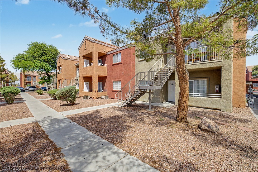 4730 East Craig Road, Unit 1091 Las Vegas, NV 89115 - Photo 1 of 23 Concrete pathways connect multi-level stucco residences framed by mature desert trees.
