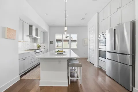 a kitchen with kitchen island white cabinets and stainless steel appliances