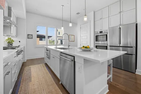 a kitchen with stainless steel appliances a stove a sink a refrigerator white center island and cabinets