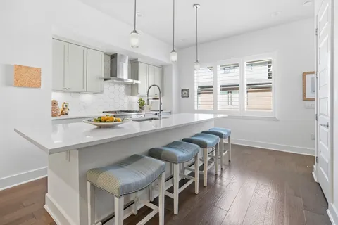 a kitchen with granite countertop a table chairs stove and white cabinets