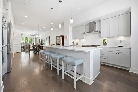 a kitchen with stainless steel appliances kitchen island granite countertop a table chairs sink and cabinets