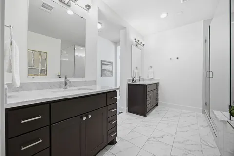 a bathroom with a double vanity sink a mirror and a bathtub