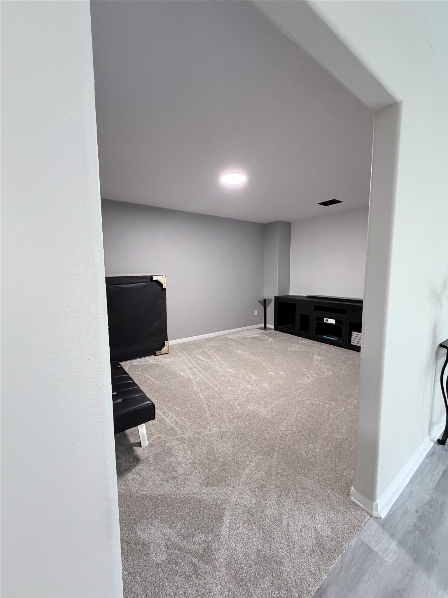 3226 Dappled Vale Trail Spring, TX 77373 - Photo 16 of 26 This room features a cozy, carpeted space with neutral gray walls. It's equipped with recessed lighting and a built-in entertainment unit, ideal for a home theater or media room setup.