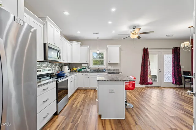 a kitchen with granite countertop kitchen island stainless steel appliances sink cabinets and wooden floor