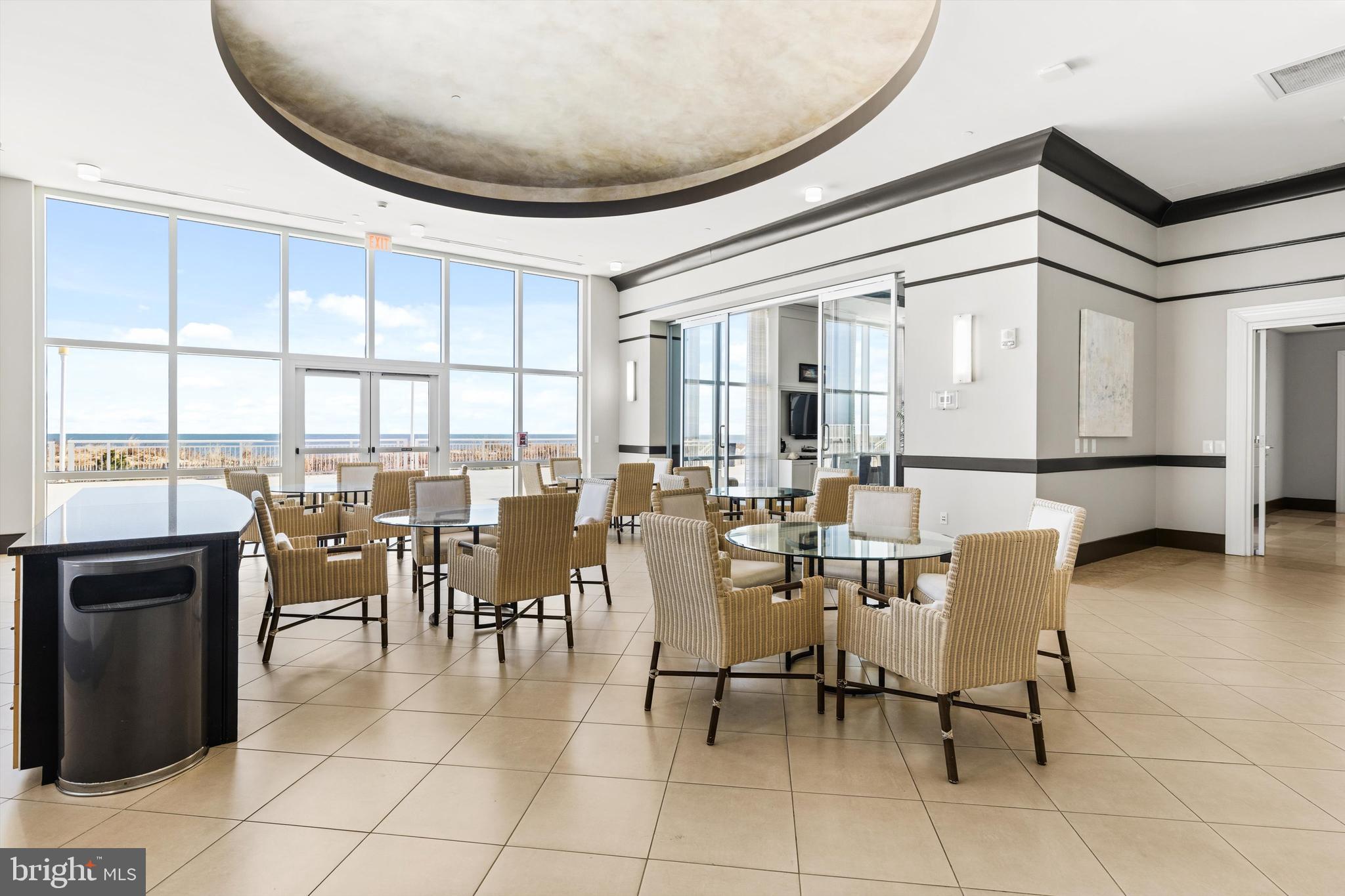 2 48th Street, Unit 1612 Ocean City, MD 21842 - Photo 65 of 90 a dining room with furniture a flat screen tv and a floor to ceiling window