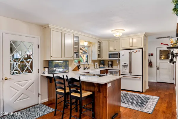 a kitchen with a refrigerator a stove a dining table and chairs with wooden floor