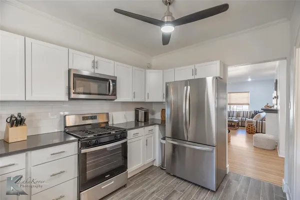 a kitchen with stainless steel appliances a refrigerator stove and white cabinets