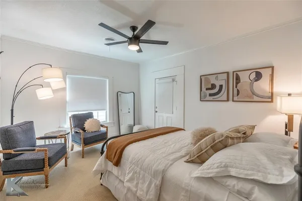 a bedroom with a bed a couch and a potted plant on the dresser