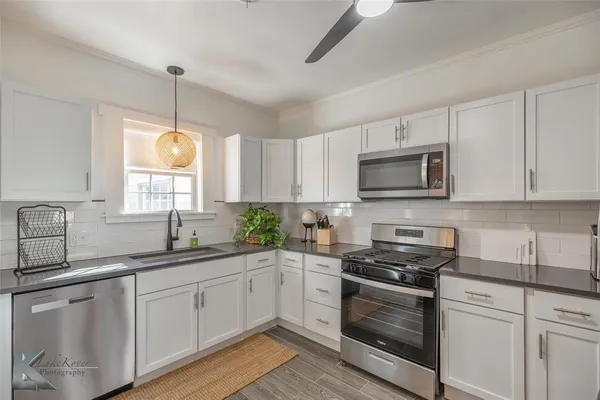 a kitchen with white cabinets appliances a sink and a window