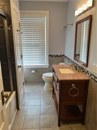 a bathroom with a sink a toilet a mirror and window