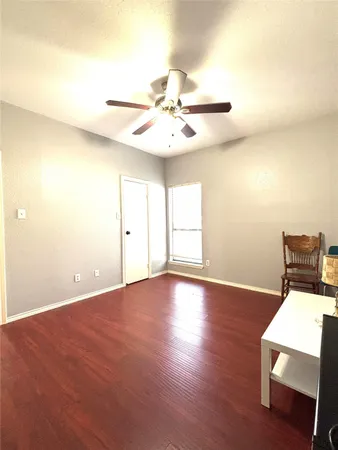 a view of an empty room with chandelier fan and wooden floor