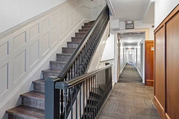 a view of staircase with lots of frames on wall and wooden floor