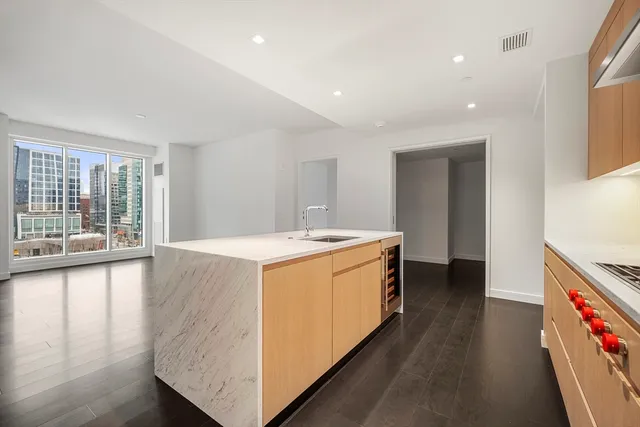 a large kitchen with stainless steel appliances granite countertop a large counter top and a wooden floors
