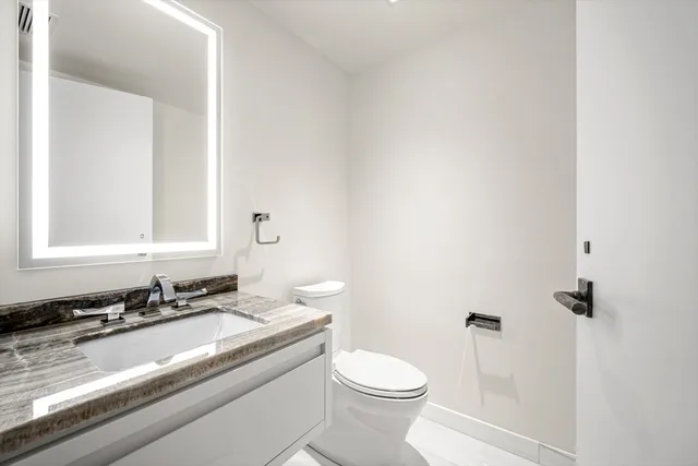 a bathroom with a granite countertop sink a toilet and a mirror