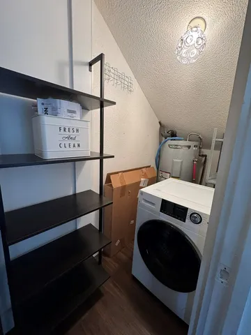 an empty room with wooden floor chandelier and windows