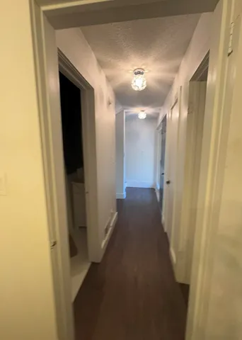 a view of an empty room with wooden floor fireplace and a window
