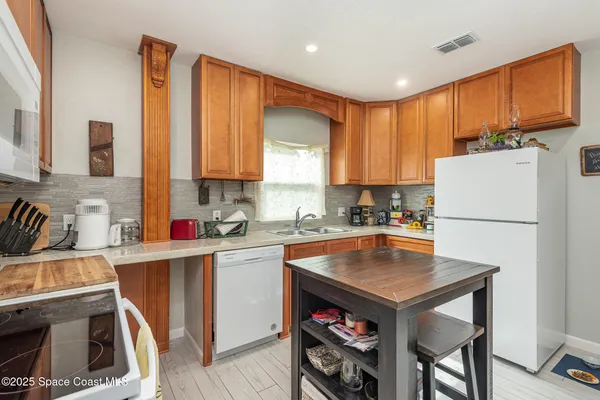 a kitchen with a refrigerator a stove a sink dishwasher and wooden cabinets