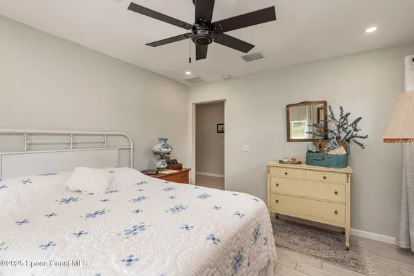 a bedroom with a bed a dresser and a potted plant