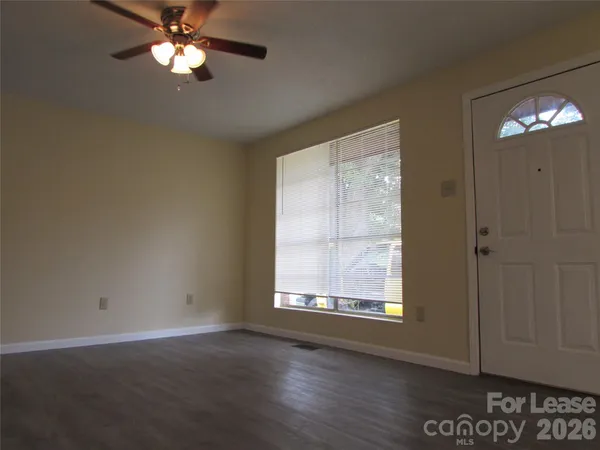 an empty room with wooden floor fan and windows