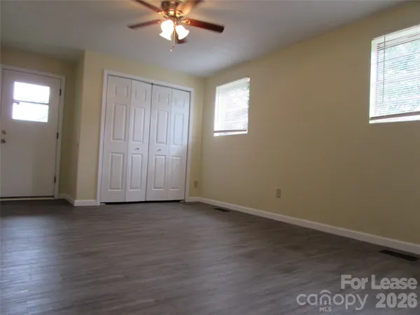 a view of an empty room with wooden floor and a window