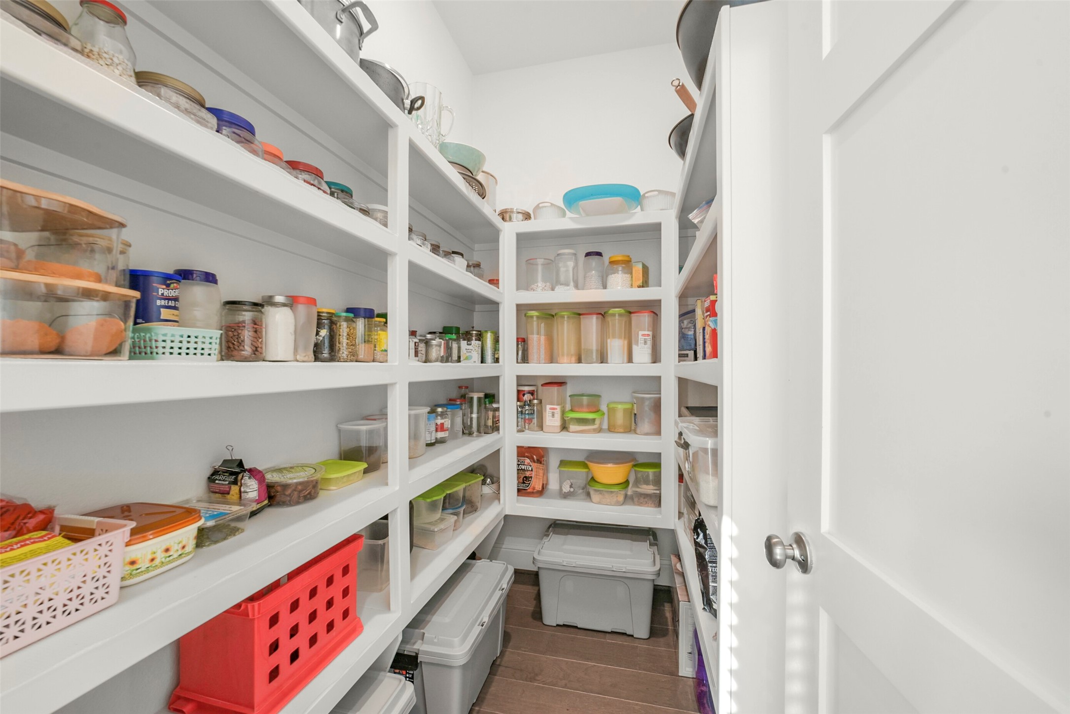 2018 Grove Terrace Lane Manvel, TX 77578 - Photo 12 of 50 Well-organized pantry with white shelving, stocked with various jars, containers, and bins for storage. The space is bright and functional, offering ample room for organizing kitchen essentials.