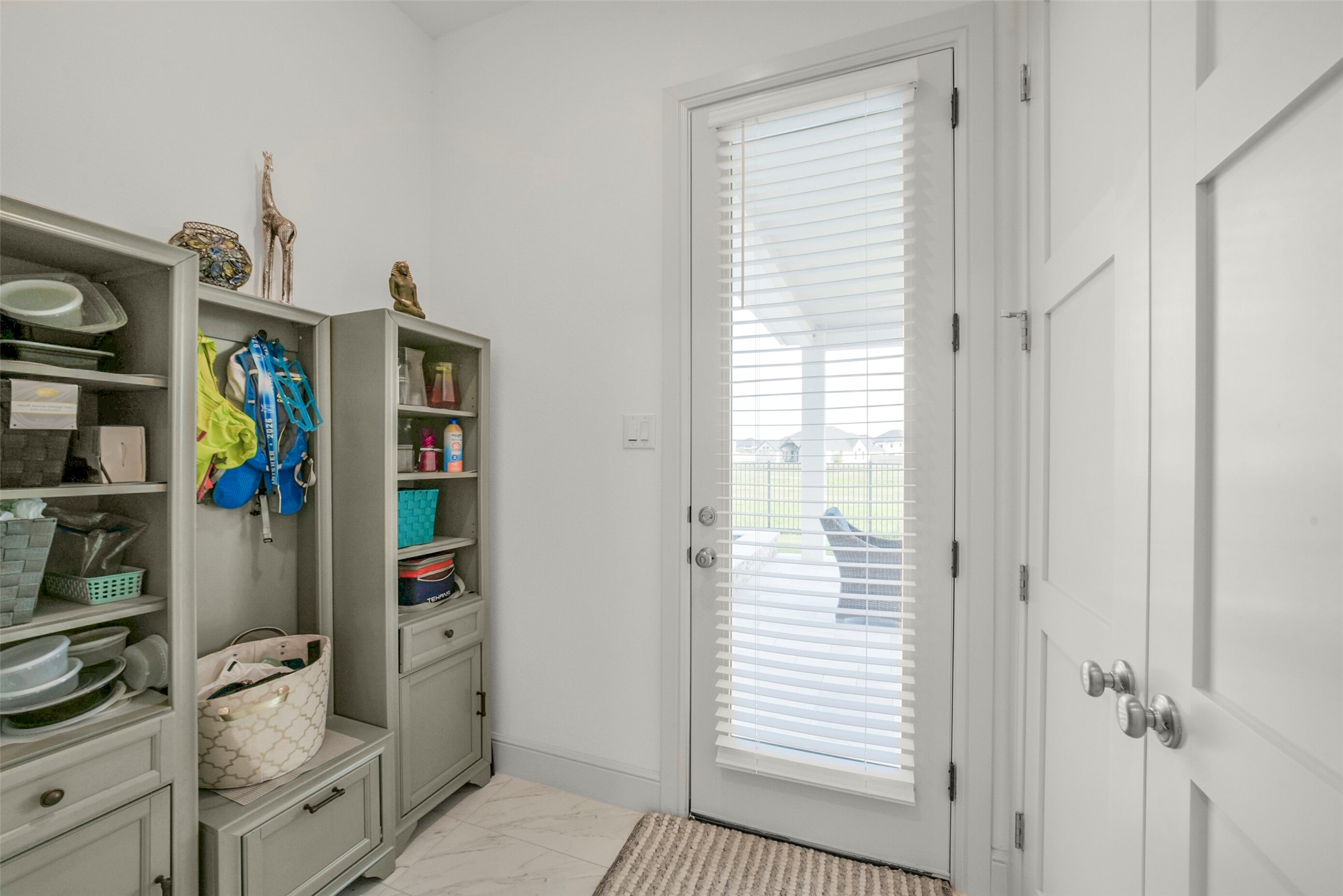 2018 Grove Terrace Lane Manvel, TX 77578 - Photo 13 of 50 One of two mudrooms with built-in storage, shelves for organization, and a door with blinds leading to an outdoor patio. The space is bright and functional, ideal for keeping daily essentials organized.