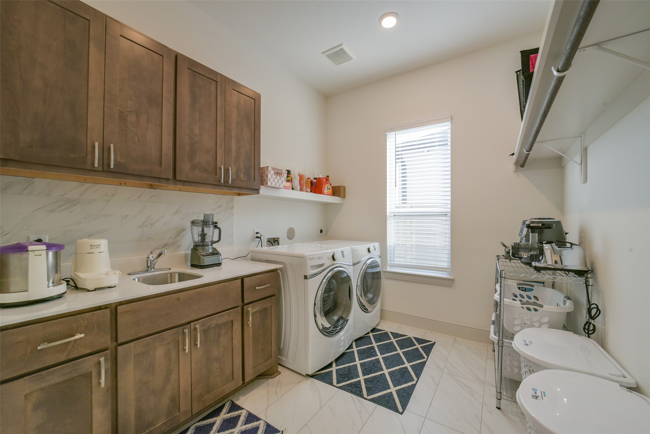 2018 Grove Terrace Lane Manvel, TX 77578 - Photo 16 of 50 This spacious laundry room features modern appliances, ample cabinet storage, a sink, and a bright window. It offers a functional and stylish space for laundry tasks.