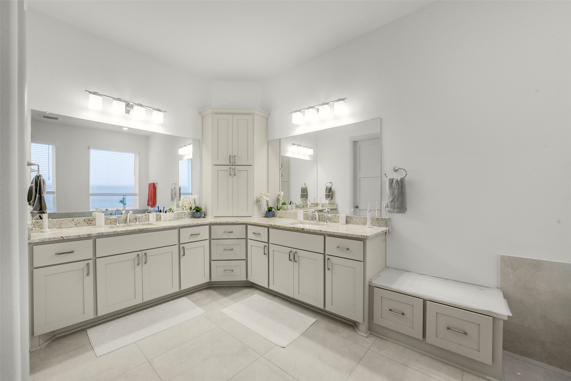 2018 Grove Terrace Lane Manvel, TX 77578 - Photo 24 of 50 This expanded bathroom features a dual-sink vanity with ample custom maple storage, modern lighting fixtures, and a clean, neutral color palette, offering a bright and functional space.