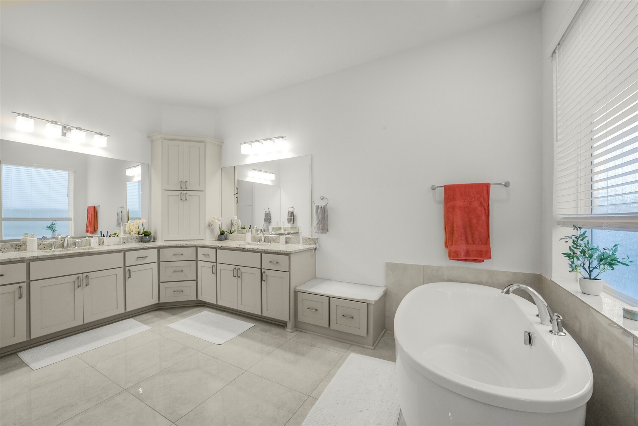 2018 Grove Terrace Lane Manvel, TX 77578 - Photo 25 of 50 This expanded upgraded primary suite bathroom features a modern design with dual sinks, ample cabinetry, and a large corner vanity. It includes a luxurious freestanding bathtub, elegant lighting, and neutral tones for a serene atmosphere.